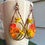 Thumbnail: long copper teardrop earrings beaded with green, yellow, and orange glass bead flowers and leaves