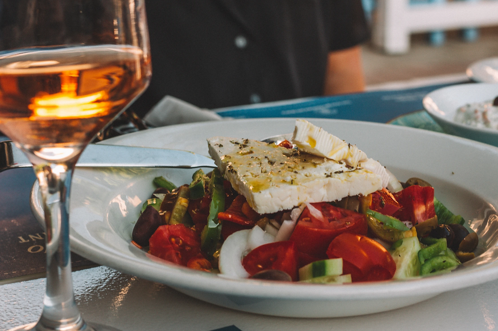 prato com salada grega acompanhado de vinho branco na taça