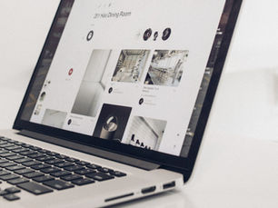 Laptop displaying interior design images and text on the screen, set on a white surface. The mood is minimal and modern.