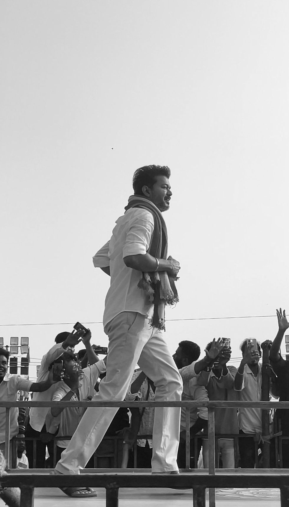 A black and white picture of Actor Vijay, TVK Head, in white shirt and red scarf