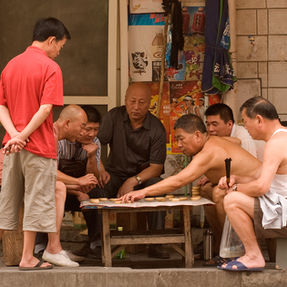 Groep volwassenen die een bordspel spelen op straat in Beijing, China.