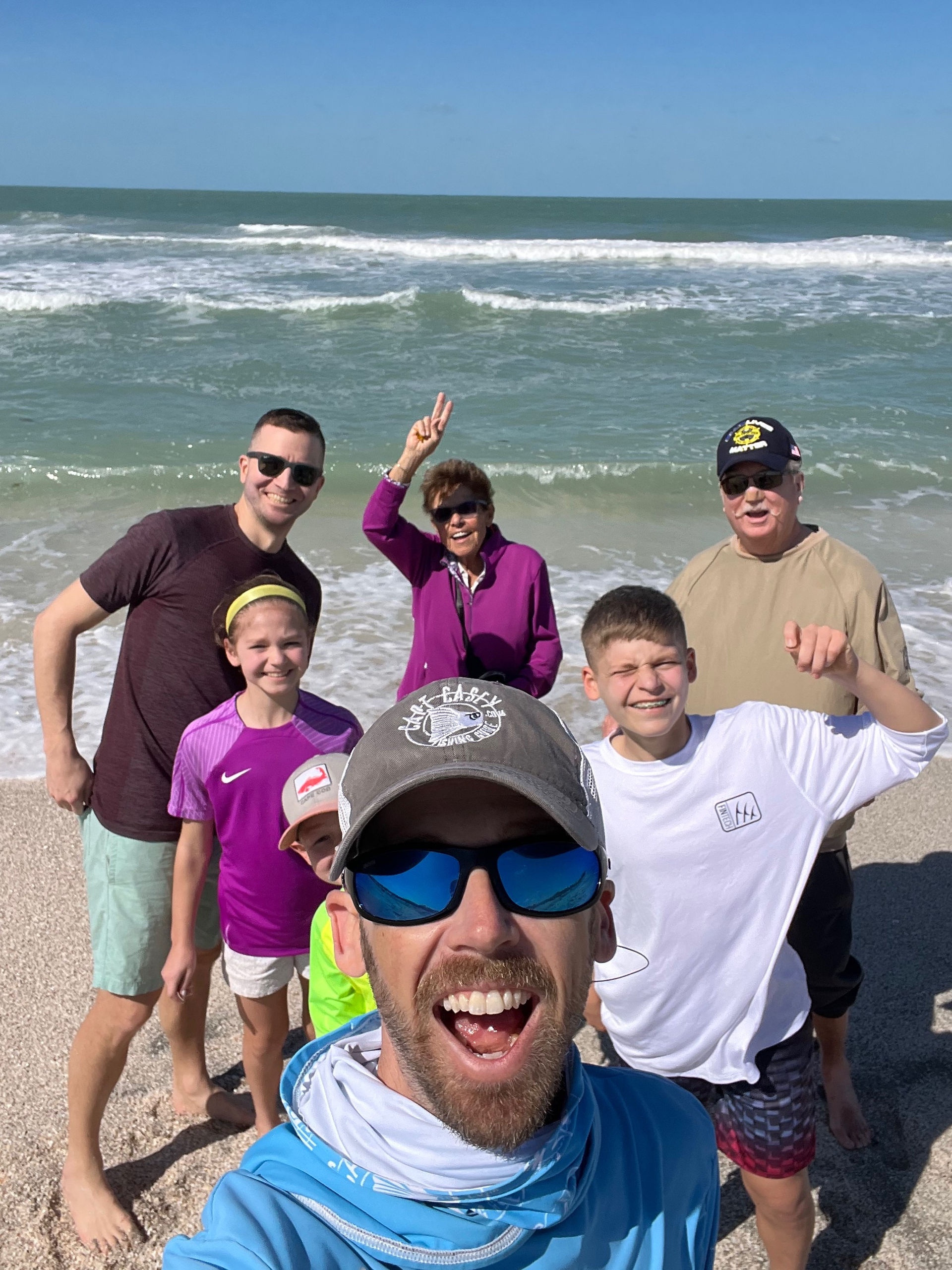 Capt.Casey taking a picture on the sandbar with a family during a family fishing charter with Sarasota Saltwater Adventures