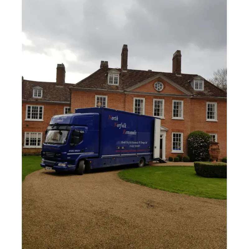 Blue removals van parked on the driveway of a large house