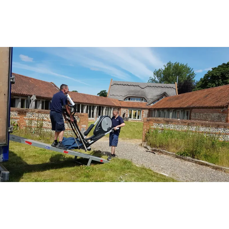 Two men carrying a large item into a house