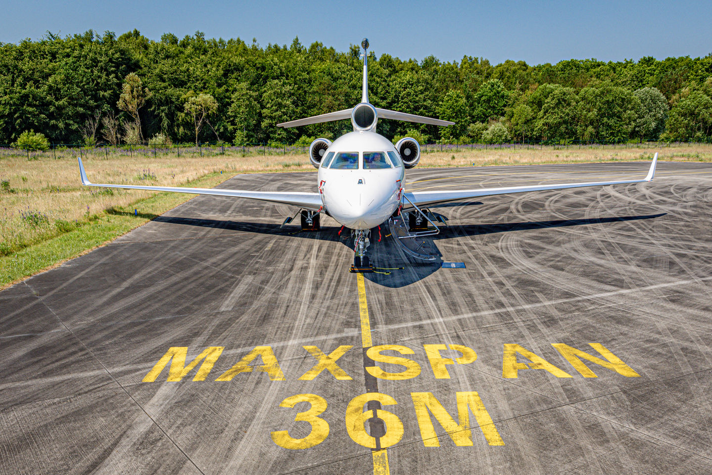 Private jet parked at runway markings at Amsterdam airport awaiting catering service.