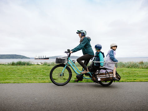 mom and two kids riding e cargo bike