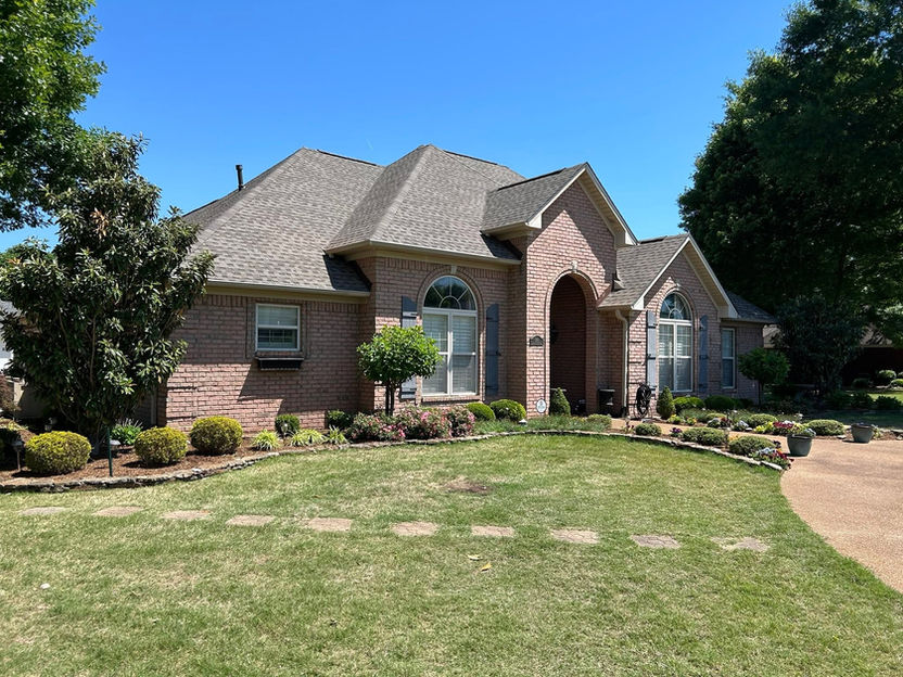Single-story brick house with a manicured front lawn.