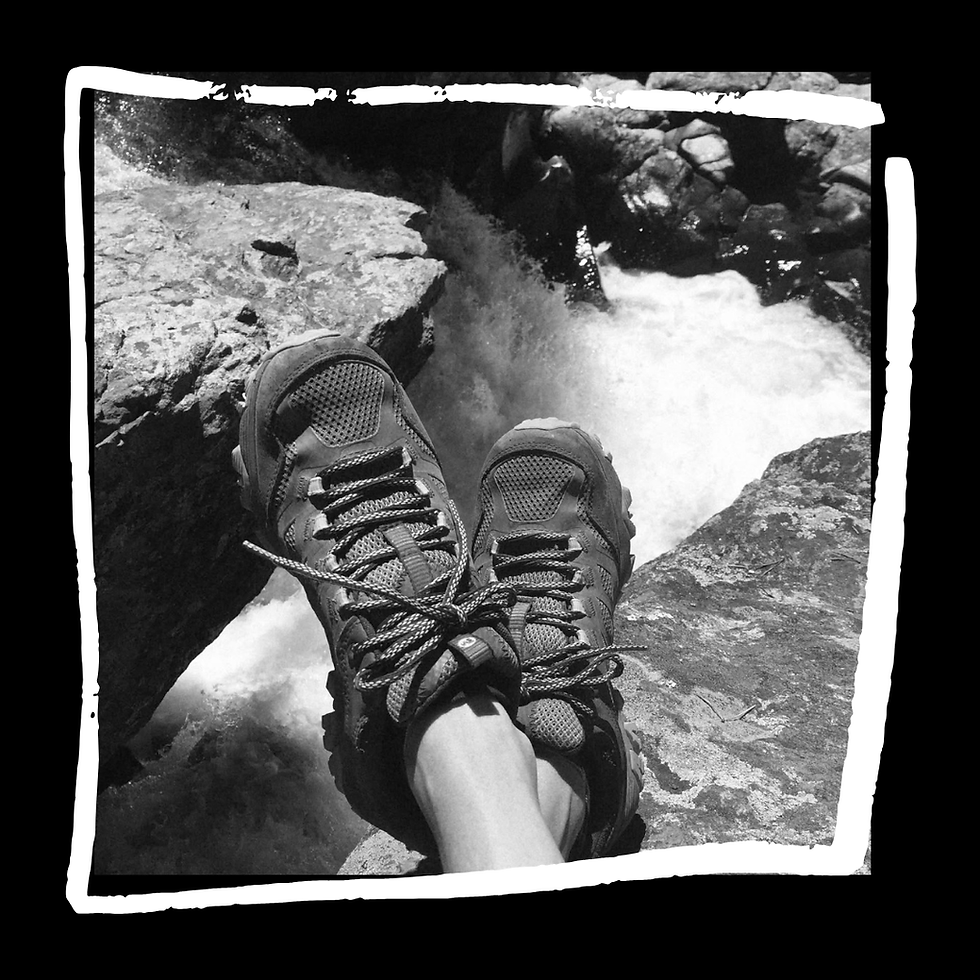 Hiking boots resting on a sunlit rock outdoors.