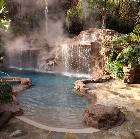 Custom swimming pool and rock work by Crystal Pools in Pacific Palisades with steaming tropical pool with rock waterfall and palm trees