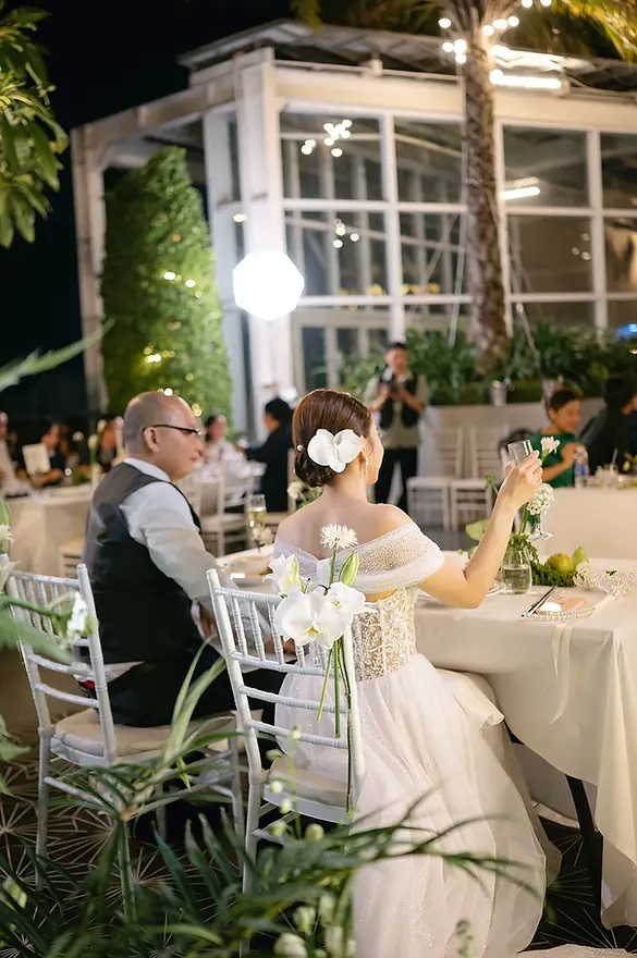 Khoảnh khắc cô dâu nâng ly chúc mừng trong tiệc cưới buổi tối với không gian ấm cúng