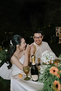 Cô dâu chú rể cười rạng rỡ bên bàn tiệc ngoài trời