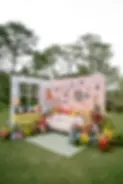 Colorful outdoor wedding lounge decorated with flowers, framed photos, and a cozy sofa.