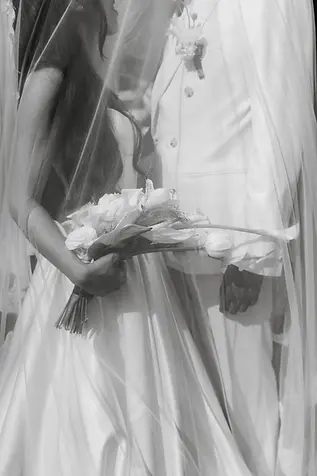 Bride holding a calla lily and rose bouquet beside the groom, both wrapped under her veil in black and white