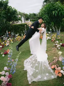 A joyful moment as the groom lifts the bride during an outdoor garden wedding, surrounded by colorful flowers.