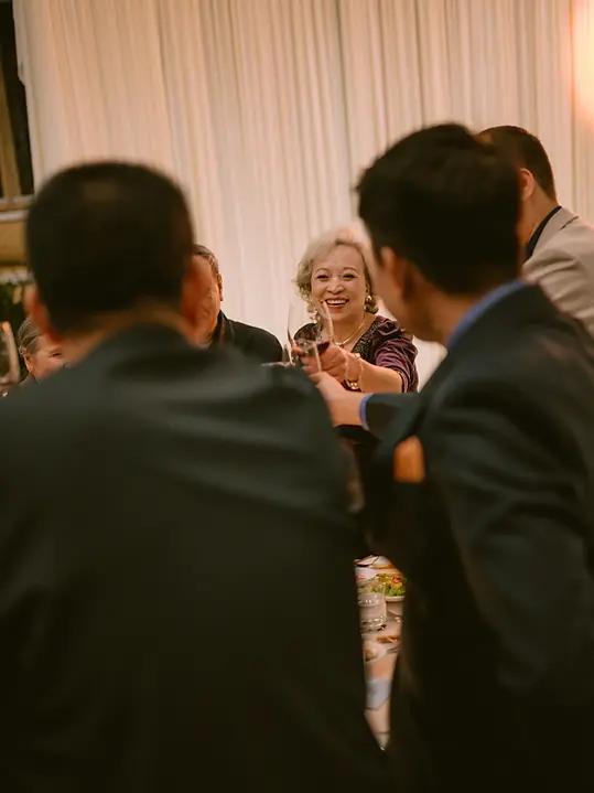 Mẹ nâng ly chúc mừng trong bữa tiệc cưới, nở nụ cười rạng rỡ giữa không khí sum vầy của gia đình và bạn bè.