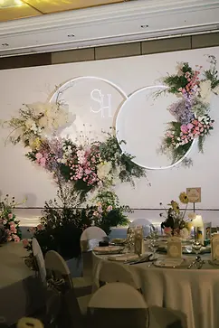 Wedding reception stage decorated with layered floral arrangements and circular backdrop design.