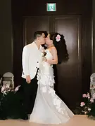 Kiss Cam 01: Bride and groom sharing a kiss at the entrance of the wedding reception space.