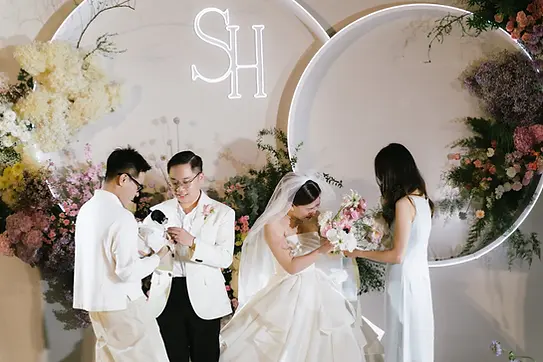 Bride and groom smiling as friends hold their small dogs on the decorated ceremony stage.