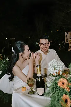 Bride and groom sharing a joyful laugh at their candlelit outdoor wedding table