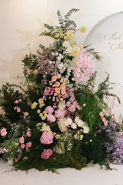 Large floral installation with pastel flowers arranged as a backdrop for the ballroom wedding space.