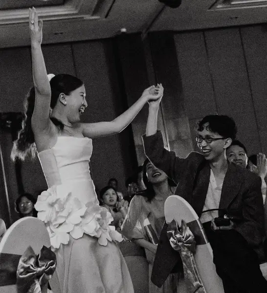 Bride dancing with guests and raising their hands together during the wedding party.