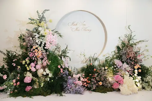 Garden-inspired floral backdrop with pastel flowers and greenery arranged around a circular wedding sign.