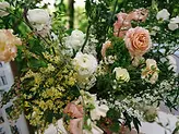 Cận cảnh hoa trang trí tông pastel với cách cắm tự nhiên, xen kẽ nhiều lớp hoa và lá xanh.