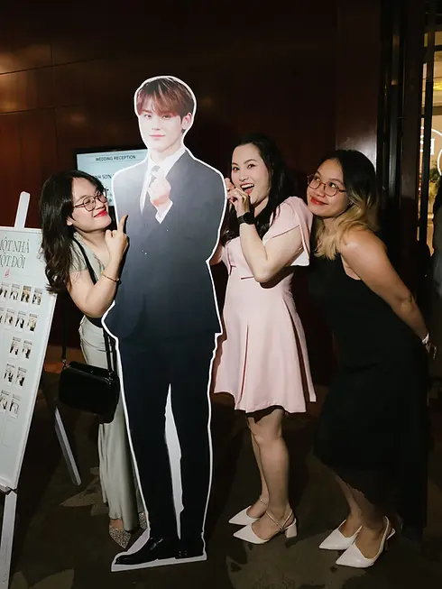 Guests posing playfully with a life-size cardboard cutout during the wedding reception.