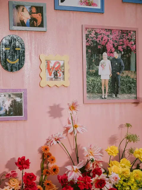 Framed photos displayed on a pink backdrop surrounded by colorful flowers.
