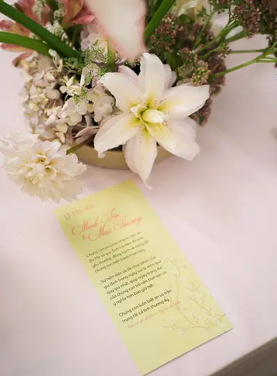 Wedding invitation card placed next to a delicate floral arrangement on a tea ceremony table.