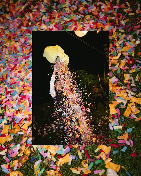 A playful confetti moment during an outdoor wedding game, with colorful paper pieces bursting into the night air.