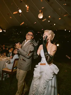Couple entering the reception while guests clap as confetti falls from above.