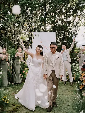 Joyful garden wedding ceremony exit in Da Lat with guests tossing flower petals.