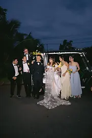 Nhóm bạn thân cùng cô dâu chú rể đứng bên xe điện trang trí hoa, ghi lại khoảnh khắc rộn ràng và ấm áp trong buổi tối ngày cưới.