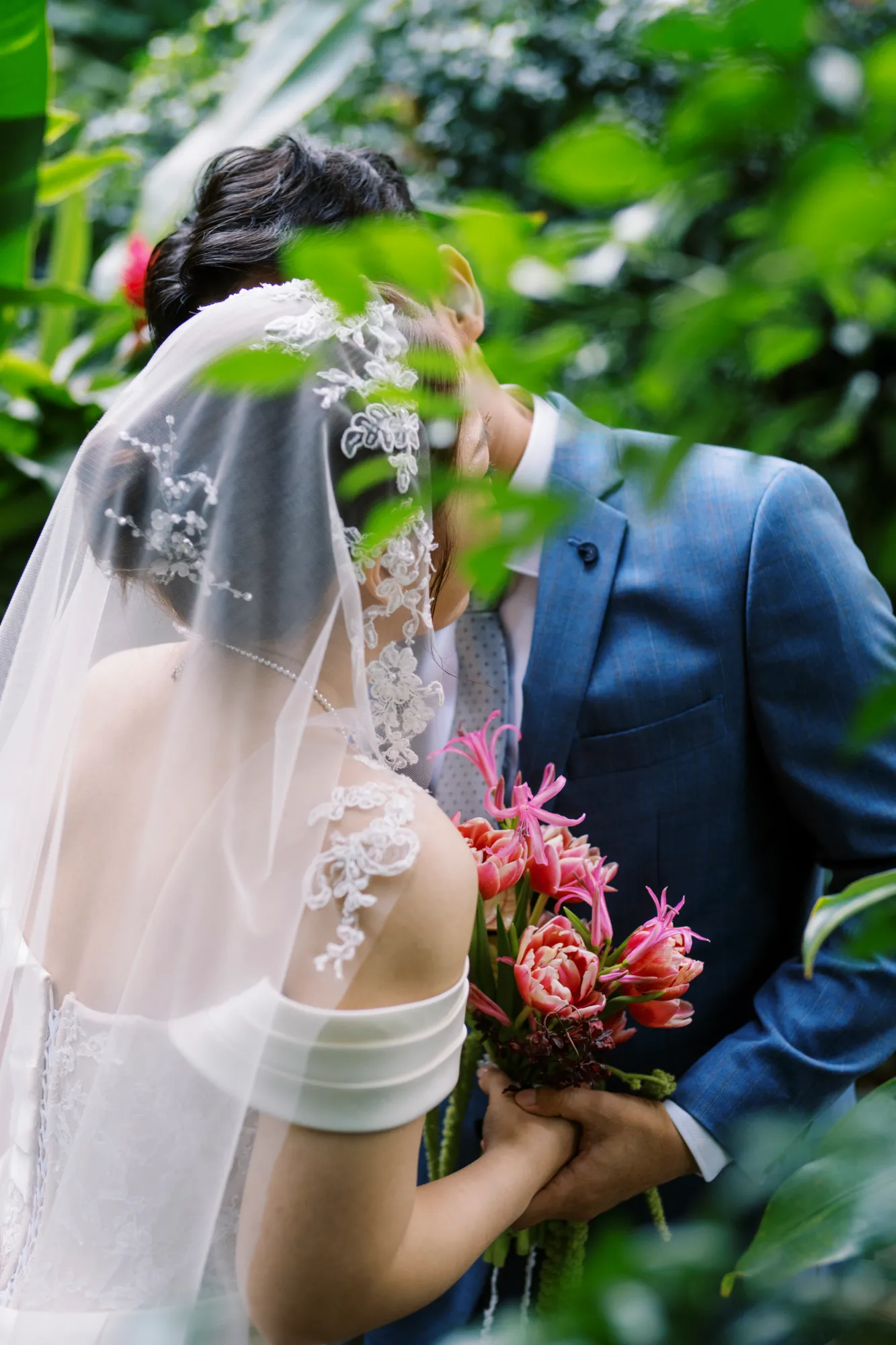 Cặp đôi chụp ảnh hôn nhau trong một khu vườn xanh.