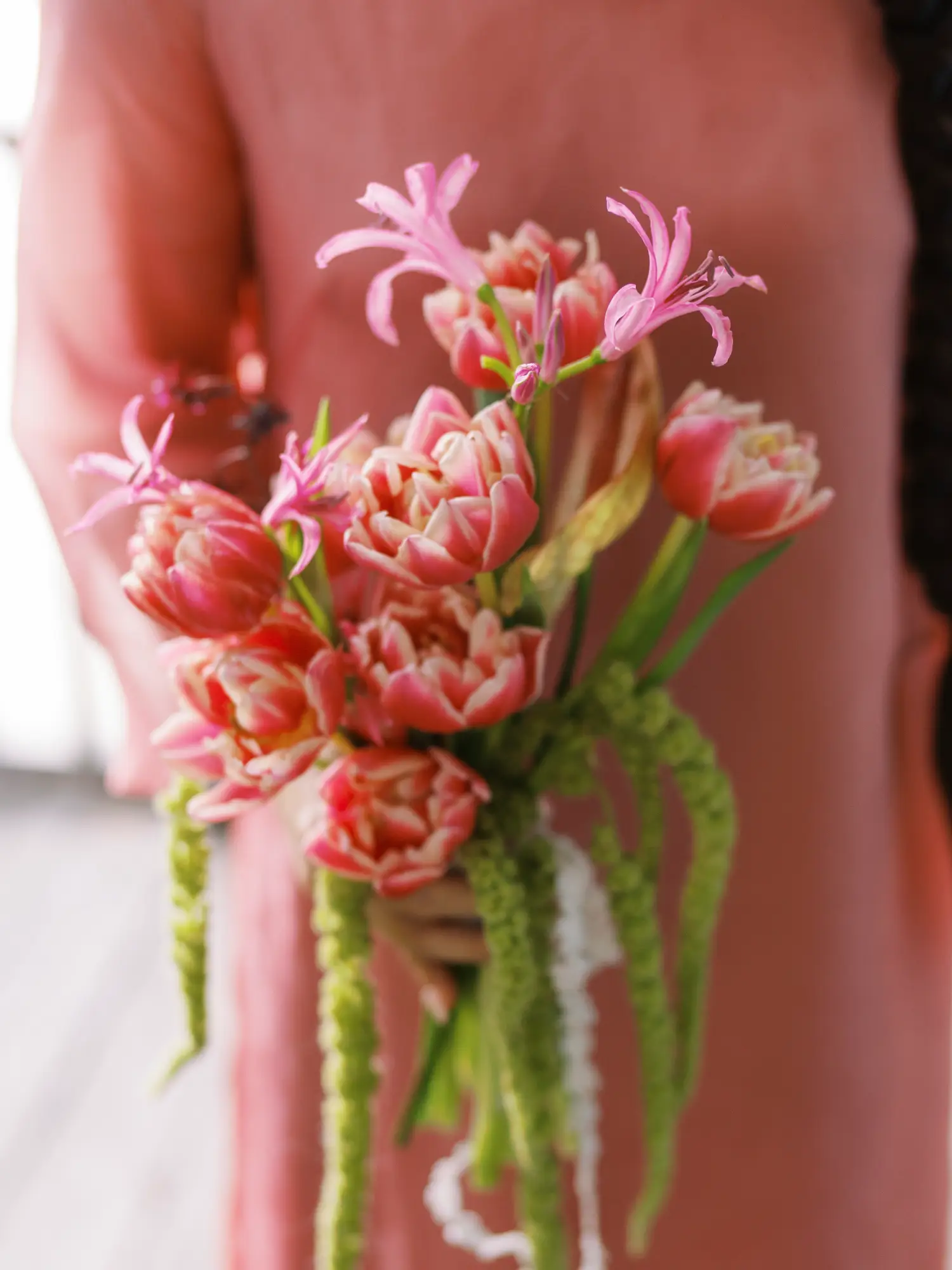 Viet bride holding a pink floral bouquet matching her áo dài during the Vietnamese traditional tea ceremony.