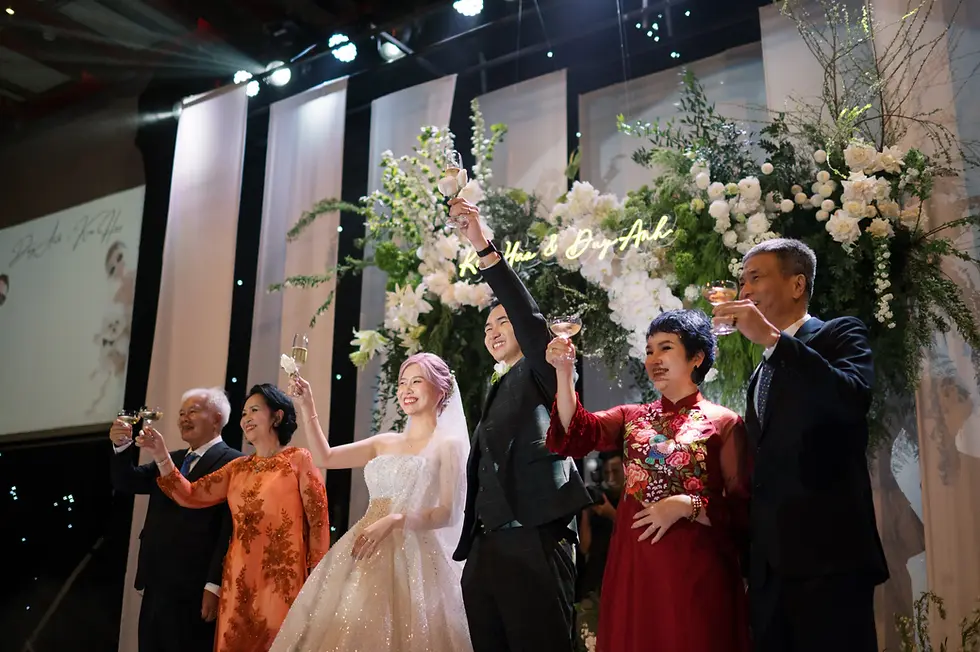 Bride, groom and parents raise their glasses on stage.