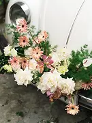 Close-up of pastel roses and orchids arranged on the front of a vintage wedding car.