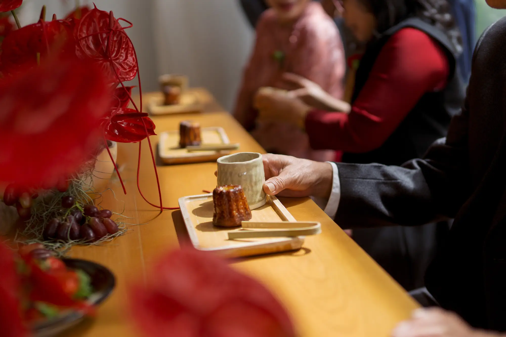 Close-up of a Vietnamese traditional tea ceremony table with tea cups, sweet cakes, and red floral decorations, reflecting the family’s care and hospitality.