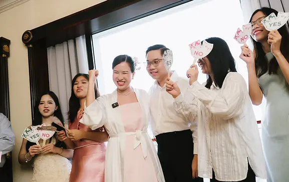 Friends holding playful yes and no signs during a lively wedding door game.