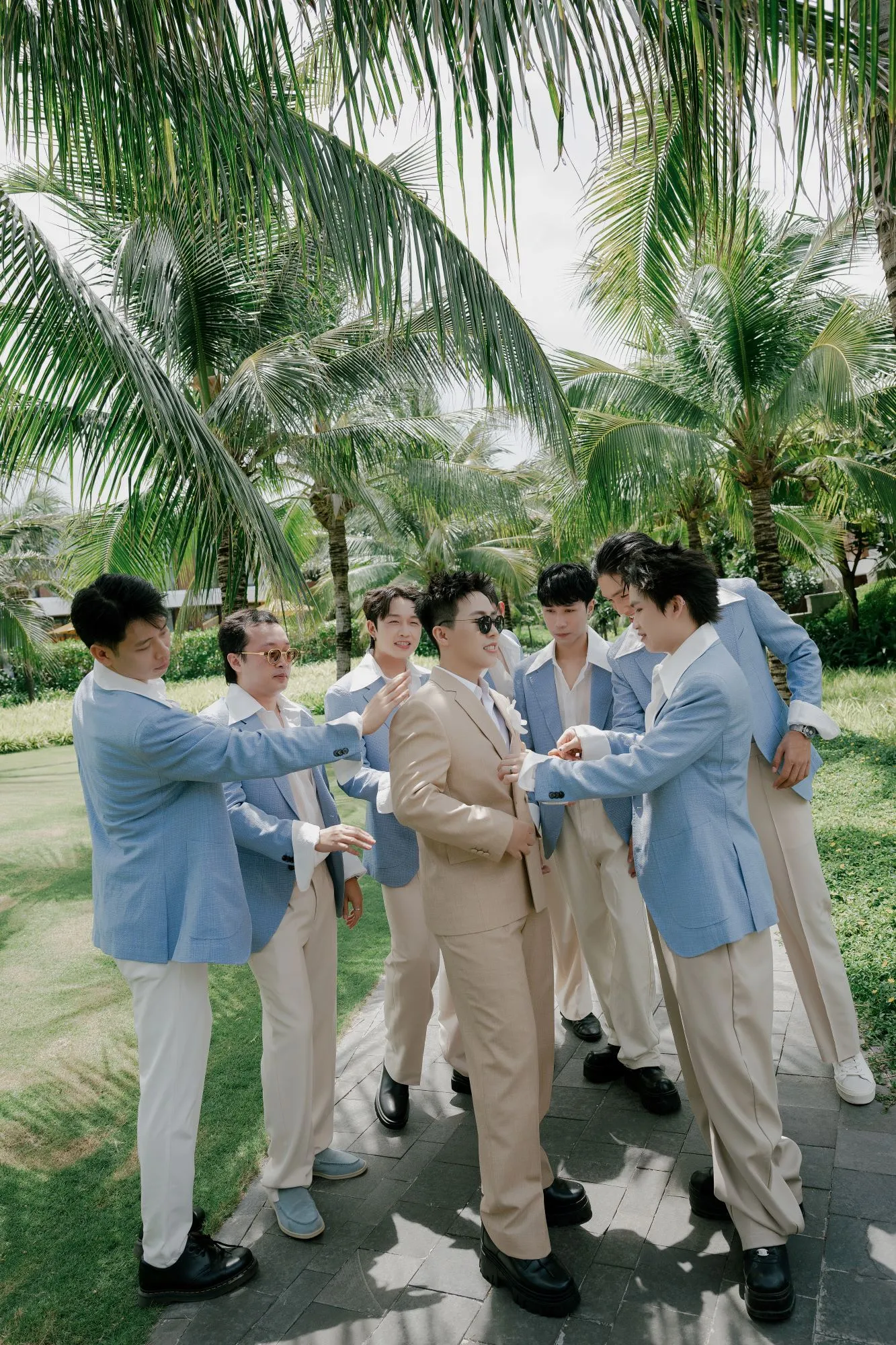 Phù rể chỉnh trang phục cho chú rể ở ngoài trời.