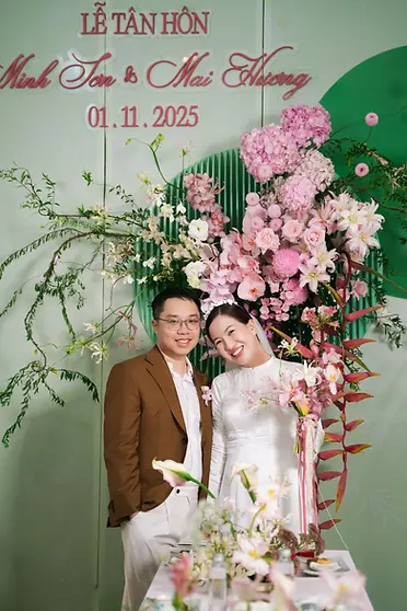 Bride and groom posing in front of a floral backdrop prepared for the tea ceremony.