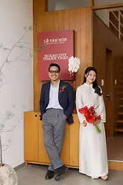 Wedding couple posing in front of a welcome sign with red floral accents