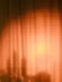 Warm light glowing through draped curtains creating soft silhouettes.