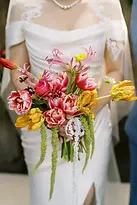 Bó hoa cầm tay cô dâu rực rỡ với sắc hồng và vàng được chụp ở góc cận cảnh.