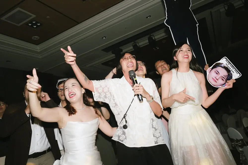 Guests singing into a microphone and dancing together during the wedding party.