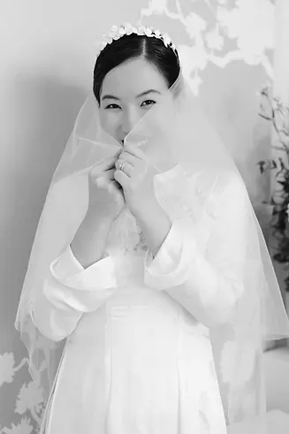 Black-and-white portrait of a bride smiling softly behind her veil.