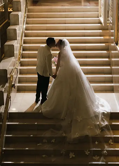Silhouette of a bride and groom sharing a kiss on a grand staircase at night.
