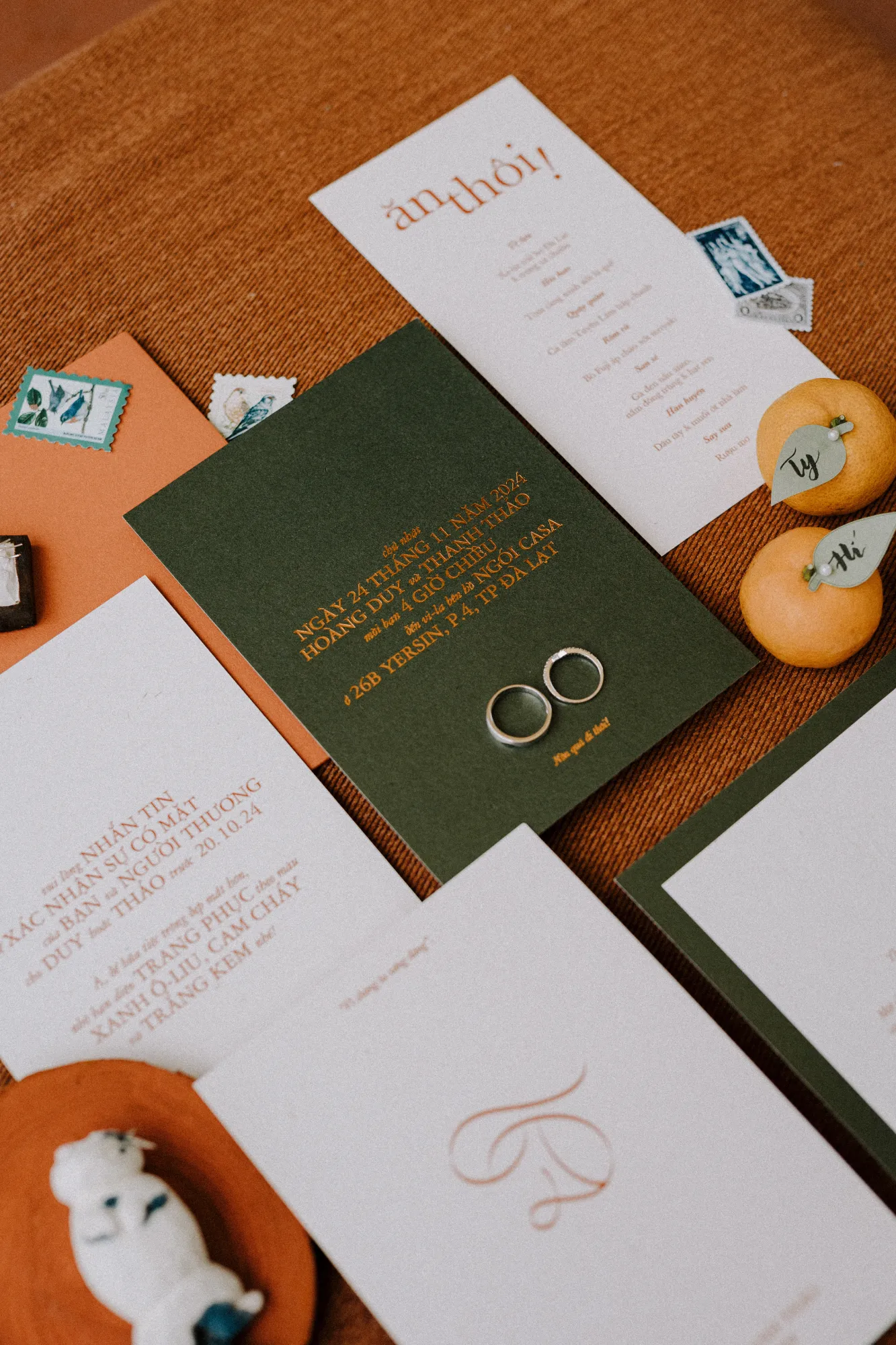 Bộ thiệp cưới dễ thương được sắp đặt nghệ thuật với tông màu xanh rêu và cam đất.