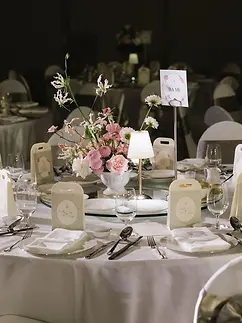 Reception table decorated with soft floral centerpieces, candles, and elegant place settings.
